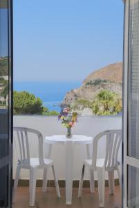 uma mesa branca com duas cadeiras e um vaso com flores em Hotel Loreley em Ischia