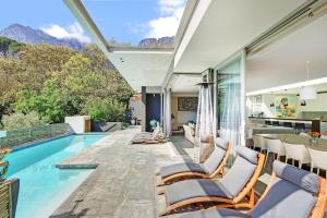 a house with a swimming pool with chairs and a table at Blinkwater Villa in Cape Town