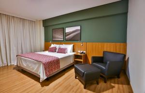 a hotel room with a bed and a chair at Comfort Mogi Guaçu in Mogi Guaçu +85 photos