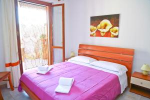 a bedroom with a pink bed with two white towels on it at Costa Mediterranea Holiday Homes in Campofelice di Roccella +36 photos