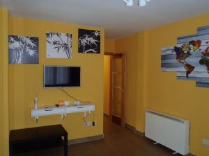 a room with a desk and a tv on a yellow wall at El Balconcito de San Millan II in Segovia