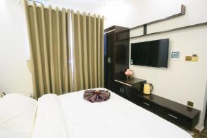 sypialnia z białym łóżkiem i telewizorem w obiekcie Pham Ha Hotel w Hajfong