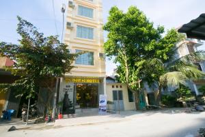 a building on a street with trees in front of it at Pham Ha Hotel in Hai Phong