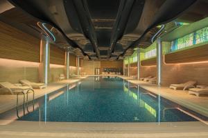 a swimming pool with benches and chairs in a building at Bayır Diamond Hotel & Convention Center Konya in Konya