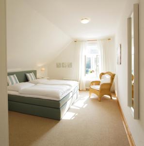 a bedroom with a bed and a chair and a window at Gut Kattenhöhlen in Scharbeutz