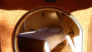 a bedroom with a bed in a round mirror at Cabane-hobbit de Samsaget in Eyvignes-et-Eybènes