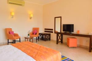 1 dormitorio con 1 cama, TV y sillas en Viva Blue Resort and Diving Sharm El Naga (Adults Only), en Hurghada