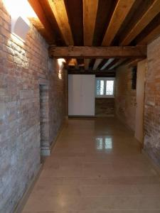 um quarto vazio com uma parede de tijolos e tectos em madeira em Gioiello di Venezia, Suite San Lio em Veneza