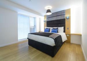 ein Schlafzimmer mit einem großen Bett mit blauen Kissen in der Unterkunft Zinn Apartments - City Centre in Aberdeen