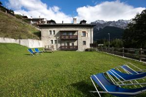 two lawn chairs sitting in the grass in front of a house at Casa del Sol Apartaments in Bormio