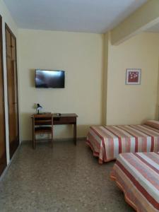 a room with two beds and a desk and a television at Hotel Borja in El Puig