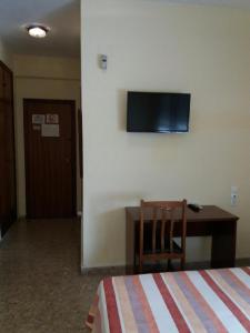 1 dormitorio con cama, escritorio y TV en la pared en Hotel Borja, en El Puig