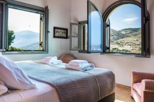 a bedroom with two beds and two windows at Myrtos Bay Apartments in Anomeriá