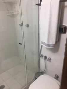 La salle de bains est pourvue d'une douche en verre et de toilettes. dans l'établissement Barra Summer flat, à Salvador