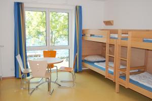a dorm room with bunk beds and a table and chairs at Jugendherberge Ratzeburg am See in Ratzeburg