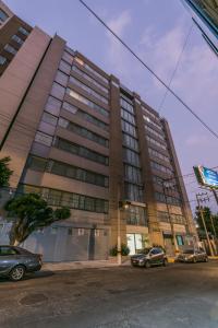 un gran edificio con coches estacionados frente a él en Suites Perisur Apartamentos Amueblados, en Ciudad de México