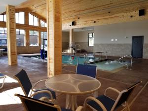 einen Pool mit einem Tisch und Stühlen in einem Gebäude in der Unterkunft Baymont by Wyndham Oacoma in Oacoma