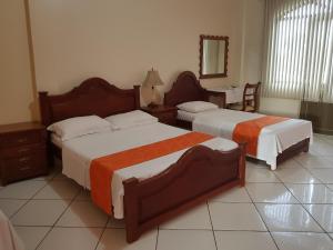 タバチンガにあるHotel Takanaのベッド2台と鏡が備わるホテルルームです。