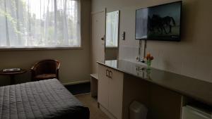 ein Schlafzimmer mit einem Bett und einem TV an der Wand in der Unterkunft Daylesford Central Motor Inn in Daylesford