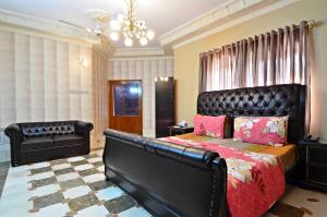 Schlafzimmer mit einem großen Bett mit einem Kopfteil aus Leder in der Unterkunft Hotel Blue Sky Executive in Karatschi
