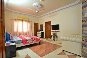 ein Schlafzimmer mit einem Bett, einem Sofa und einem TV in der Unterkunft Hotel Blue Sky Executive in Karatschi