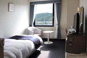 um quarto de hotel com uma cama e uma janela em Hotel Verfort Hyuga em Hyuga