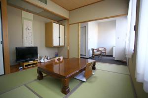 a living room with a table and a television at Hotel Verfort Hyuga in Hyuga