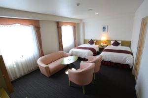 日向にあるホテルベルフォート日向のベッド2台とソファが備わるホテルルームです。