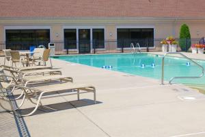 una piscina con sillas, una mesa y un edificio en Best Western Galleria Inn & Suites en Cheektowaga