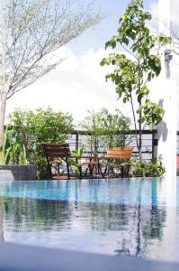 a pool of water with two benches and trees at Monsoon Bassac Hotel in Phnom Penh