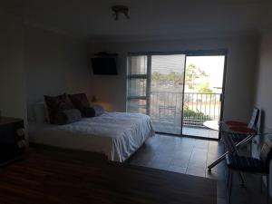 a bedroom with a bed and a sliding glass door at San Norina Gardens in Bloubergstrand