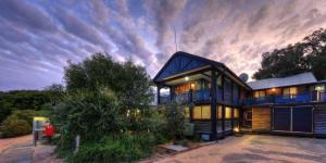 a large house with a cloudy sky behind it at Fraser Island Retreat in Fraser Island