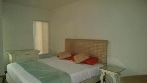 a bedroom with a bed with two red pillows at Solari Casa de Huespedes in Rosarito