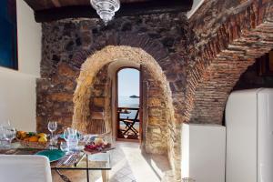 Cette chambre avec vue dispose d'un mur en pierre et d'une voûte avec une table. dans l'établissement Nido al Mare - by Vacation Service, à Cefalù
