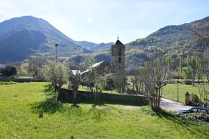 an old church in a field with mountains in the background at Apartamentos L´Era de Baix in Barruera