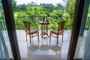 einen Balkon mit einem Tisch und 2 Stühlen sowie Aussicht in der Unterkunft Pondok Bali in Ubud