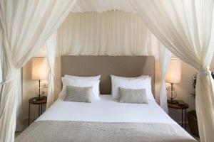 una camera da letto con un letto bianco con tende bianche di S'Hotelet d'es Born - Suites & SPA a Ciutadella