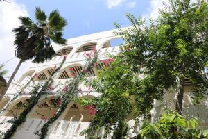 a white building with palm trees in front of it at Jamala Guesthouse in Lamu