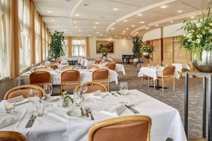 a restaurant with white tables and chairs and flowers at Hotel Winkelried am See in Stansstad