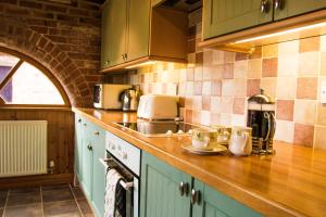 a kitchen with green cabinets and a counter top at Lodge Barns in Fiskerton