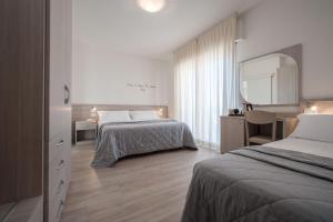 una camera d'albergo con due letti e uno specchio di Hotel Anny a Lido di Jesolo