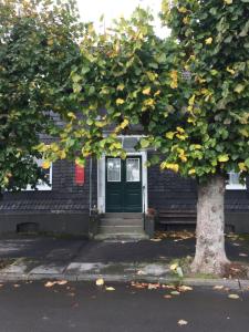 una casa con una puerta verde y un árbol en Sieben Linden, en Remscheid