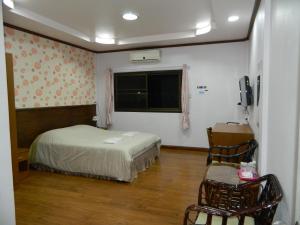 1 dormitorio con cama, ventana y silla en Garden Place, en Phetchabun