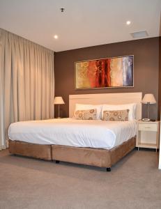 a bedroom with a large bed with a painting above it at APTonNorthTCE in Adelaide