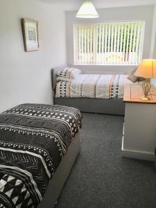 a bedroom with two beds and a table with a lamp at Snowdon Cottage in Caernarfon