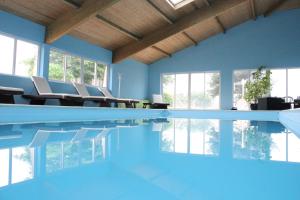 a swimming pool with chairs and blue walls at Hotel Le Chatard in Sarcey