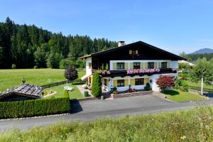 ein Haus mit schwarzem Dach und Blumen im Hof in der Unterkunft Appartementhaus Mühlberger in Ellmau