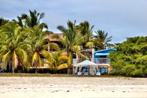 a house on the beach with palm trees at The Isabela Beach House in Puerto Villamil