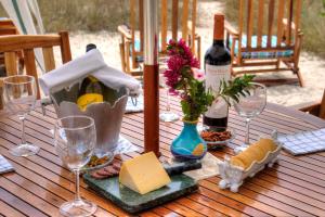 a wooden table with a bottle of wine and wine glasses at The Isabela Beach House in Puerto Villamil