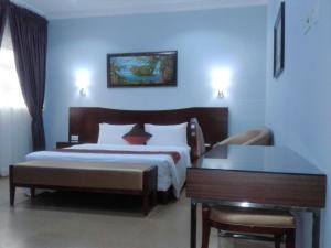 a hotel room with two beds and a table and a desk at Conference Hotel & Suites Ijebu in Ijebu Ode